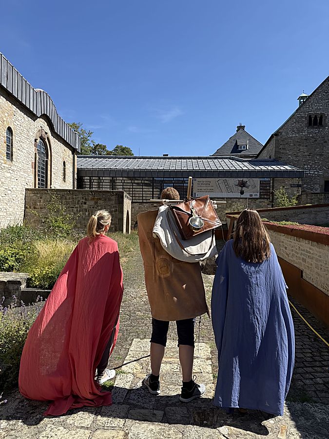 Drei Personen in römisch anmutenden Gewändern stehen im Innenhof des LWL-Museums in der Kaiserpfalz in Paderborn.Drei Personen in römisch anmutenden Gewändern stehen im Innenhof des LWL-Museums in der Kaiserpfalz in Paderborn.
