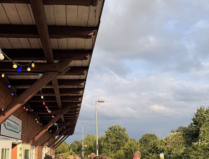 Gäste auf der Terrasse des Weberei-Bahnhofs bei einem sommerlichen Abend mit Getränken und Musik